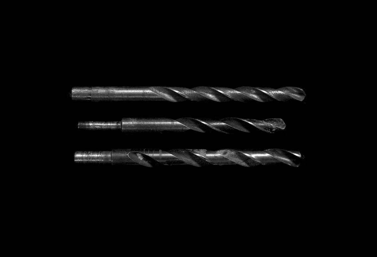 Twist drill bits laid out in monochrome, showing flute geometry and cutting edges