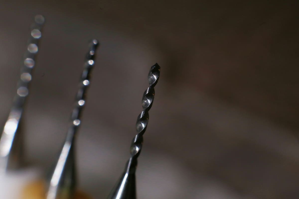 Pair of twist drills photographed close up against a dark background