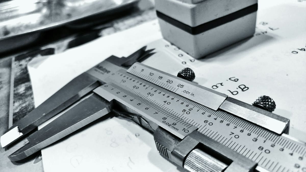 Dial caliper positioned on a technical drawing while dimensions are checked