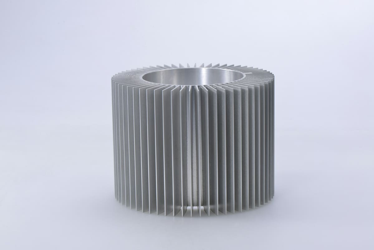 Knurled aluminium component photographed on a plain neutral background